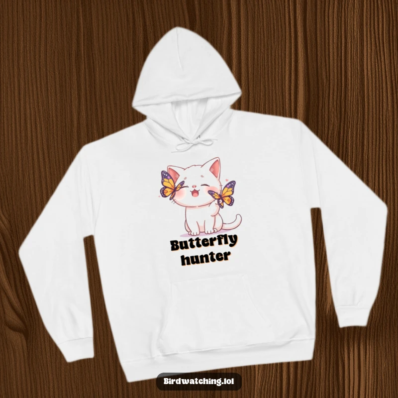 Funny hoodie depicting a giggling cat playfully trying to shoo away a colorful butterfly with a happy expression.