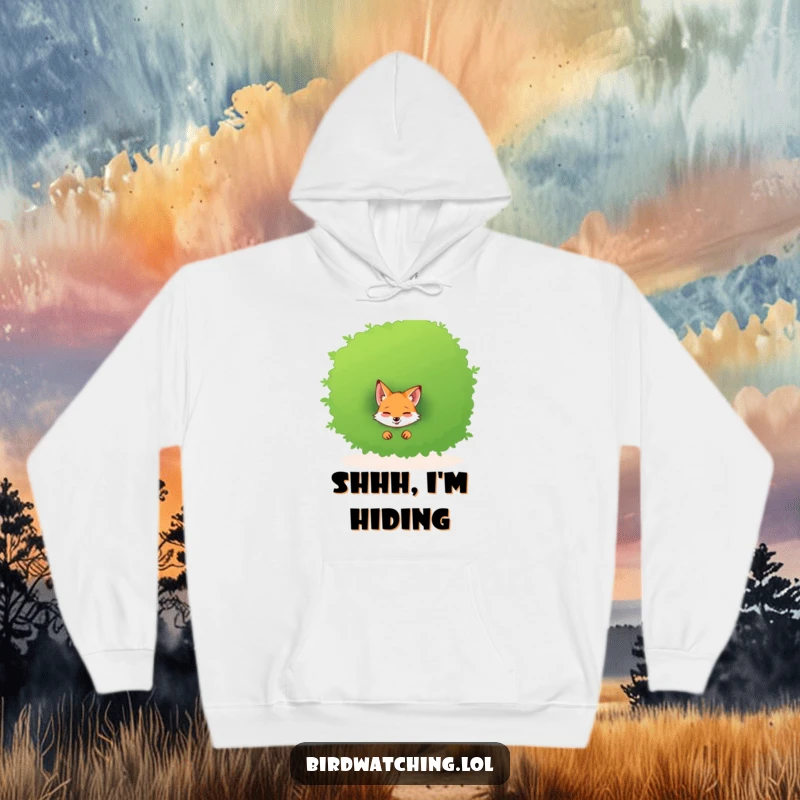 Funny hoodie featuring a giggling fox peeking out from behind a large, leafy bush, full of mirth.